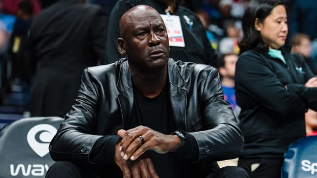 Michael Jordan sits courtside during an NBA game.